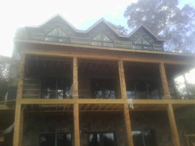 Dormers and porch framing on a large log home under construction — Roof Coating work by our crew in Williams